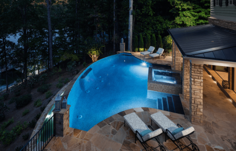 Situated on a private cove of Lake Lanier this stunning project is the essence of indoor-outdoor living and embraces all the best elements of its natural beauty. The custom pool house addition features an open floor plan with a kitchen, bar and great room and large sliding doors that lead to a luxurious infinity edge pool and negative knife edge spa. Outdoor lighting highlights the architectural silhouette of this luxurious outdoor living space and sets the mood for poolside entertaining.