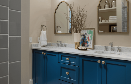 Classic guest bathroom design with blue shaker cabinets, marble countertops, under-mount double sinks, polished chrome fixtures, contemporary gold leaf mirrors and vanity sconces.