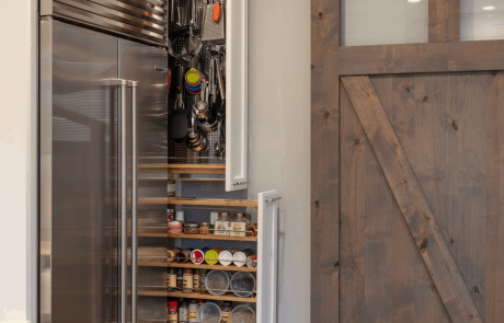 Chef’s kitchen includes white shaker custom cabinets with pull-out spice and cookware drawers. Sliding barn door separates the kitchen from the mud room.