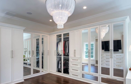 Second story addition includes large private dressing room and master closet with ample storage, white custom cabinetry and mirrored doors with polished nickel hardware and stunning two-tier chandelier. Walls are painted in Dove Wing by Benjamin Moore.