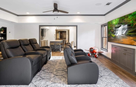 A basement home theater was a must in this custom basement remodel complete with comfortable gray leather stadium seating, large mounted flat screen TV and a high performing audio system.