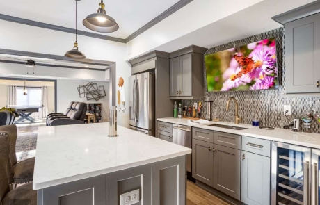 This gorgeous open-concept finished basement offers plenty of entertaining space with four distinct living spaces including a contemporary gray and white kitchen and bar area with full kitchen, wine fridge and mounted tv, home theater and family room, a game room with hidden murphy beds and a wine tasting room.