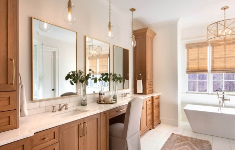 Transitional master bathroom includes a rectangular white freestanding soaker tub, white marble tile floor, white oak double vanities anchored by matching storage linen towers with light wood shaker cabinets and Viatera Forte quartz countertops with undermount sinks.