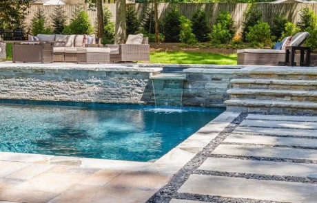 Luxury Backyard & Pool Design Features Rectangular Swimming Pool with Raised Flush Spa & Spillover, Gray Irregular Flagstone Coping, & Outdoor Entertaining Area.