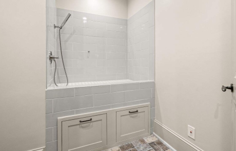 This pet-friendly, elevated wash station features a built-in dog bathing area with pull-out drawers, gray and white ceramic tile surround and multifunctional hand-held shower.