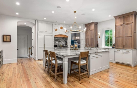 Custom kitchen renovation includes open floor plan with two-toned kitchen cabinets, oversized kitchen island, lime-washed brick accent wall, Thermador kitchen appliances, 48-Inch Dual-Fuel Pro Grand® Range, statement pendant lighting and natural wood floors.