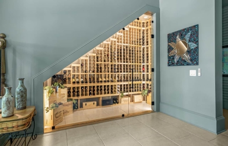 Under-staircase basement renovation features a custom wine cellar design with innovative wine storage solutions, perfect for maximizing space and adding a touch of luxury to your home.