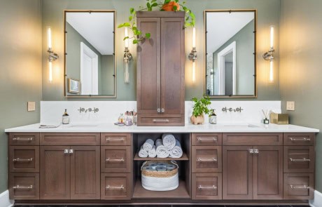 Stylish bathroom featuring a double vanity with rich wood cabinetry, quartz countertops, wall-mounted faucets, framed mirrors, and soft ambient lighting.