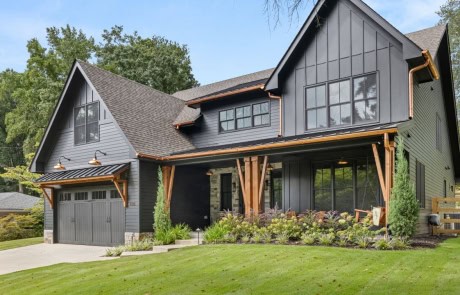 Contemporary farmhouse design in residential architecture with a bold dark exterior, board and batten siding, copper accents, and natural wood beams.